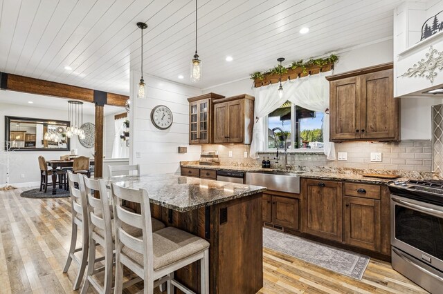33 Shale Ct, Kalispell, MT 59901 - kitchen featuring stainless steel appliances, dark stone countertops, light wood finished floors, a breakfast bar, and tasteful backsplash
