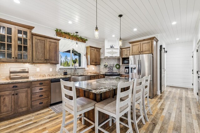 33 Shale Ct, Kalispell, MT 59901 - kitchen with appliances with stainless steel finishes, light wood finished floors, a kitchen bar, dark stone countertops, and backsplash