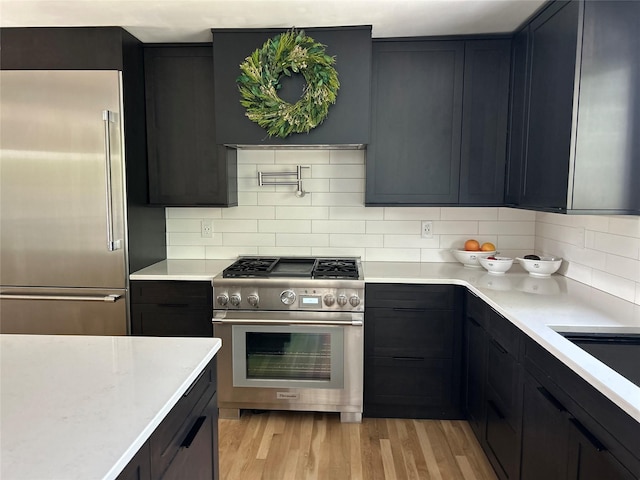 9200 River Rd, Bozeman, MT 59718 - kitchen with high end appliances, light wood-style flooring, decorative backsplash, and range hood