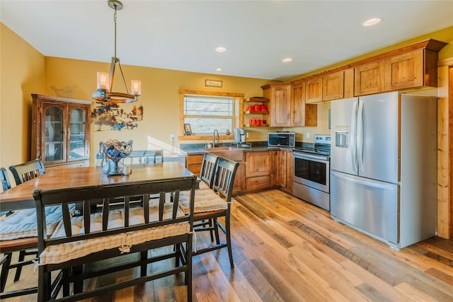 7 Papson Ridge Ln, Hall, MT 59837 - kitchen with appliances with stainless steel finishes, brown cabinetry, light wood finished floors, dark countertops, and recessed lighting