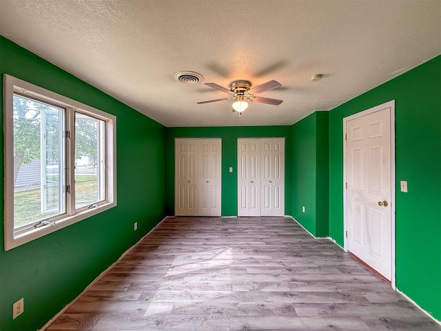 802 2nd St SW, Choteau, MT 59422 - unfurnished bedroom with two closets, a textured ceiling, wood finished floors, and ceiling fan