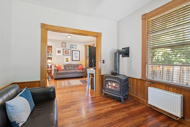 314 9th Ave W, Kalispell, MT 59901 - living room with radiator heating unit, a wainscoted wall, a wood stove, wood finished floors, and wooden walls