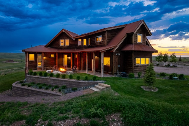 99 Little Belt Way, Belt, MT 59412 - back of house at dusk featuring a lawn, an outdoor fire pit, a patio, and metal roof