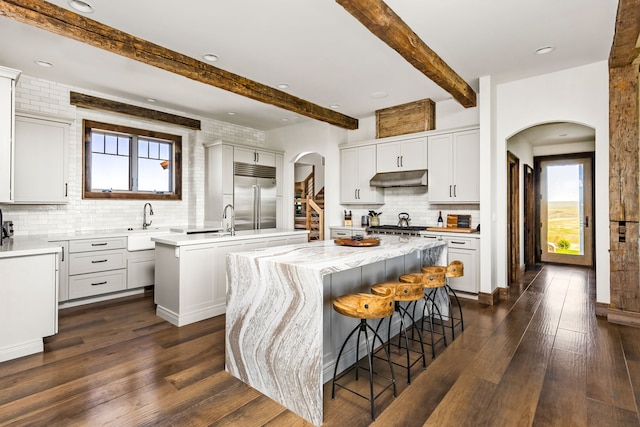 99 Little Belt Way, Belt, MT 59412 - kitchen with a center island, built in refrigerator, arched walkways, under cabinet range hood, and decorative backsplash
