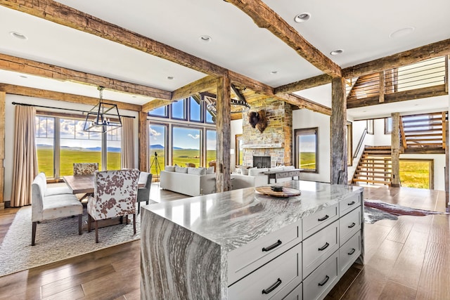99 Little Belt Way, Belt, MT 59412 - kitchen featuring healthy amount of natural light, open floor plan, a stone fireplace, beam ceiling, and light stone countertops