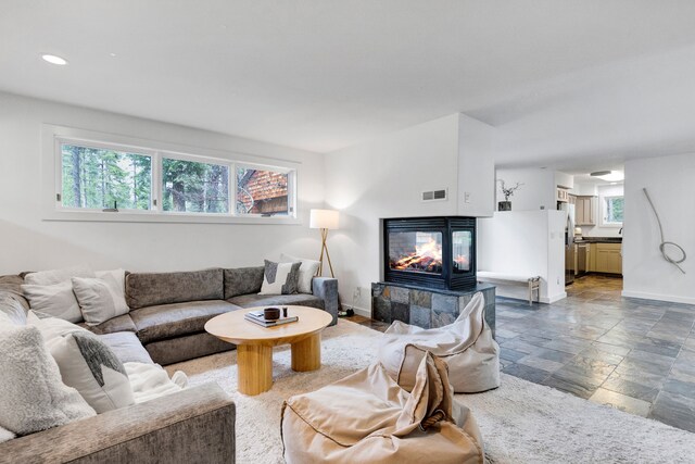 33535 Cherry Ln, Bigfork, MT 59911 - living area featuring a tiled fireplace, baseboards, stone tile floors, and recessed lighting