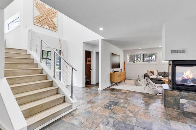 33535 Cherry Ln, Bigfork, MT 59911 - foyer featuring stone tile floors, stairway, baseboards, a multi sided fireplace, and recessed lighting
