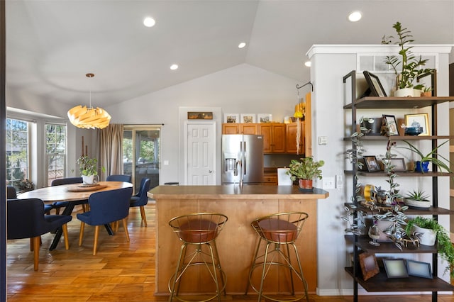 3197 Rose St, Bozeman, MT 59718 - kitchen with stainless steel fridge, vaulted ceiling, a peninsula, light wood finished floors, and brown cabinetry