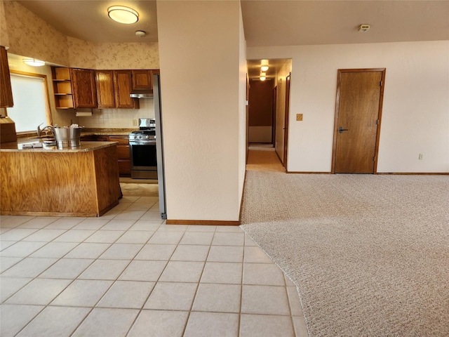 127 Patricia Way, Hamilton, MT 59840 - kitchen featuring stainless steel gas stove, brown cabinetry, open shelves, a peninsula, and light tile patterned floors