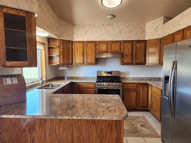 127 Patricia Way, Hamilton, MT 59840 - kitchen with stainless steel appliances, under cabinet range hood, brown cabinetry, open shelves, and decorative backsplash