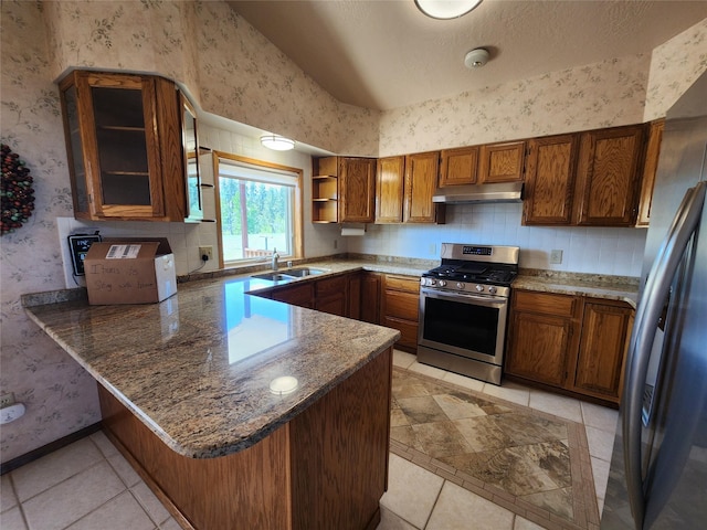 127 Patricia Way, Hamilton, MT 59840 - kitchen with appliances with stainless steel finishes, under cabinet range hood, wallpapered walls, a peninsula, and brown cabinets