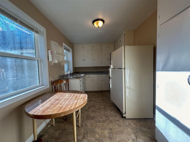 522 Main Ave N, Choteau, MT 59422 - kitchen with freestanding refrigerator, stone finish floors, dark countertops, and white cabinets