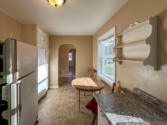 522 Main Ave N, Choteau, MT 59422 - kitchen with freestanding refrigerator, arched walkways, white cabinets, and open shelves