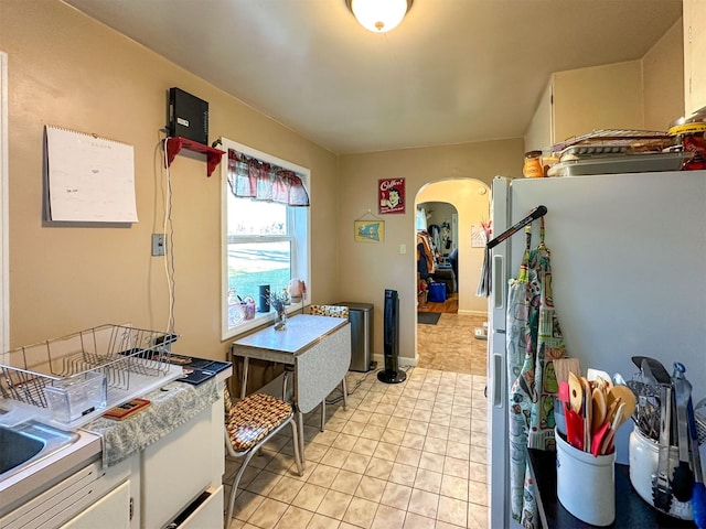 522 Main Ave N, Choteau, MT 59422 - kitchen with freestanding refrigerator, arched walkways, white cabinets, light tile patterned floors, and light countertops
