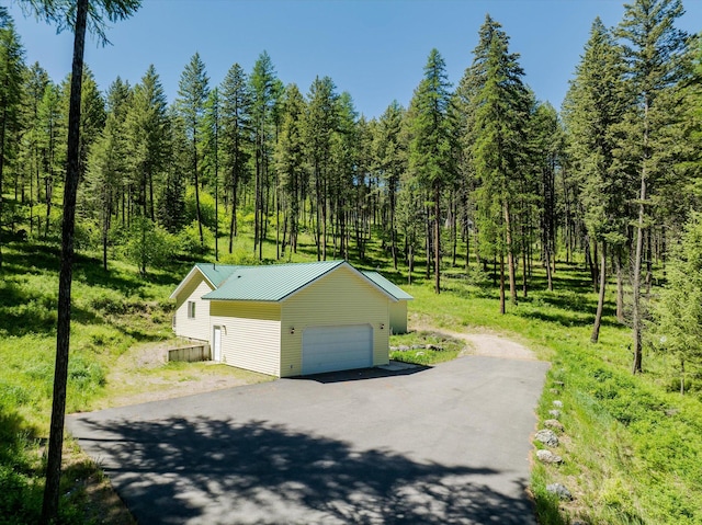 42843 Jette Lake Trl, Polson, MT 59860 - view of property exterior featuring an outbuilding, metal roof, a forest view, and a garage
