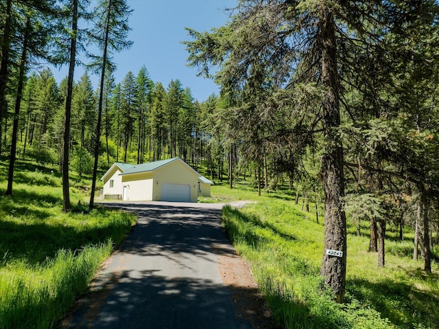 42843 Jette Lake Trl, Polson, MT 59860 - view of front of home featuring an outbuilding, asphalt driveway, a view of trees, a garage, and metal roof