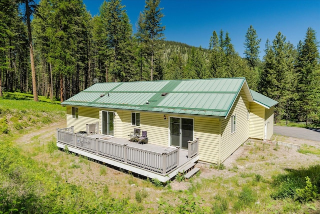 42843 Jette Lake Trl, Polson, MT 59860 - view of front of home featuring a wooded view, metal roof, and a wooden deck