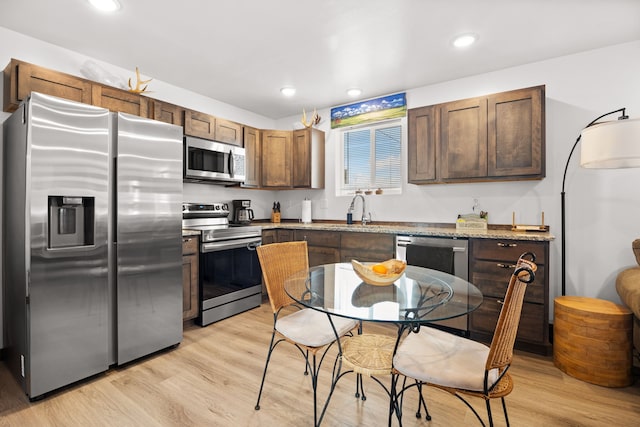 108 Timmons St, Dillon, MT 59725 - kitchen featuring appliances with stainless steel finishes, light wood-type flooring, a sink, recessed lighting, and light stone counters