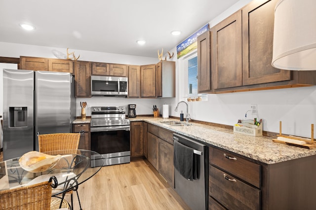 108 Timmons St, Dillon, MT 59725 - kitchen featuring appliances with stainless steel finishes, a sink, light stone counters, light wood finished floors, and recessed lighting