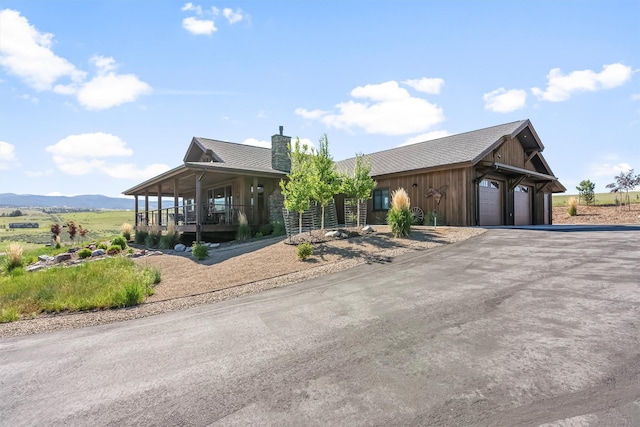 144 Prickly Pear Ct, Florence, MT 59833 - view of front facade featuring a chimney, asphalt driveway, an attached garage, and a porch