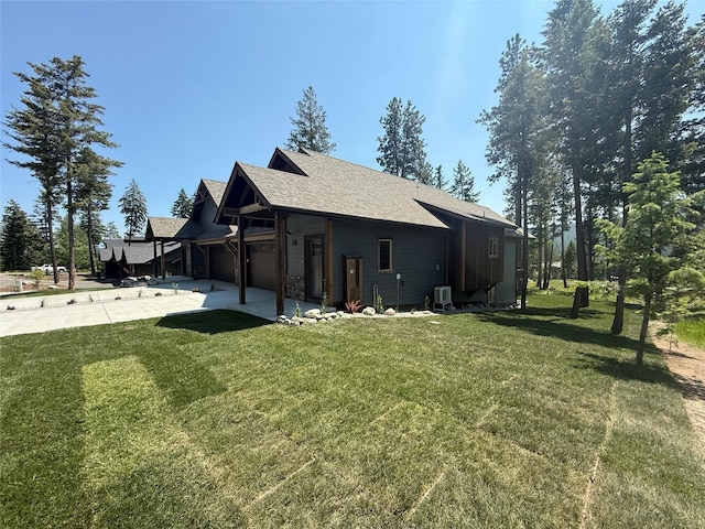 595 Grayling Rd, Lakeside, MT 59922 - rear view of house with concrete driveway, a yard, a shingled roof, a patio area, and an attached garage