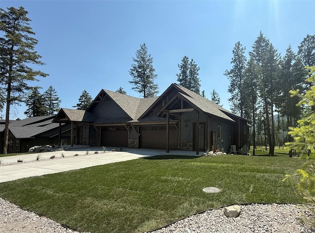 595 Grayling Rd, Lakeside, MT 59922 - view of front of home featuring a front lawn, a garage, concrete driveway, stone siding, and a shingled roof