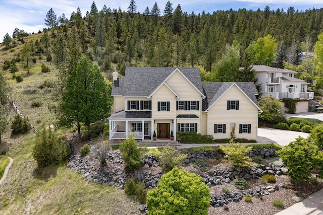 1 Reeders Village Dr, Helena, MT 59601 - traditional home featuring covered porch, a chimney, a view of trees, and roof with shingles