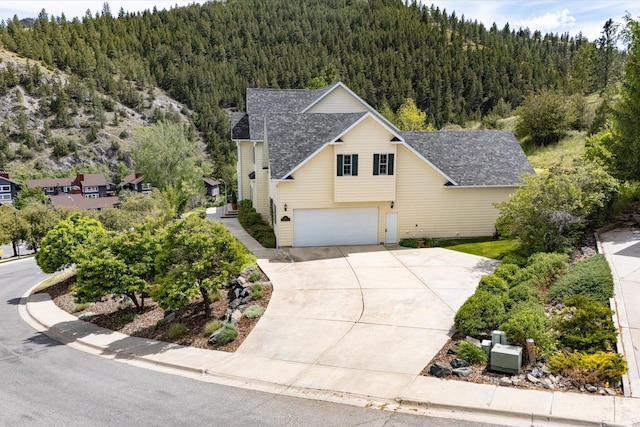 1 Reeders Village Dr, Helena, MT 59601 - view of front of home featuring a forest view, a garage, concrete driveway, and a shingled roof
