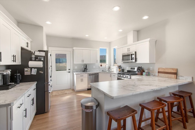 259 Meadow View Loop, East Helena, MT 59635 - kitchen with appliances with stainless steel finishes, a peninsula, a sink, light wood-style flooring, and white cabinets