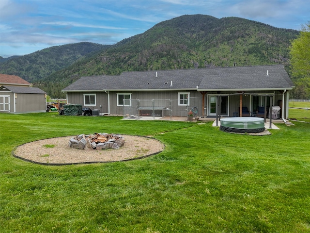 122 Bernie Rd, Alberton, MT 59820 - rear view of property with a hot tub, a fire pit, a mountain view, a lawn, and a patio area