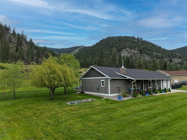 122 Bernie Rd, Alberton, MT 59820 - back of house with a chimney, a mountain view, covered porch, and a view of trees