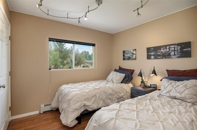 3717 Aster St, East Helena, MT 59635 - bedroom featuring baseboard heating, wood finished floors, track lighting, and baseboards