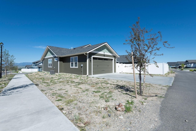 2805 Travis Ave, Helena, MT 59601 - view of side of property featuring an attached garage, concrete driveway, cooling unit, and roof with shingles