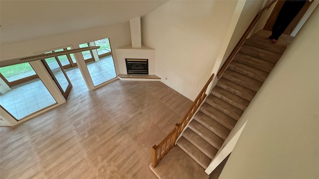 10 Pine Ridge Cir, Clancy, MT 59634 - unfurnished living room featuring a glass covered fireplace, stairway, high vaulted ceiling, and wood finished floors