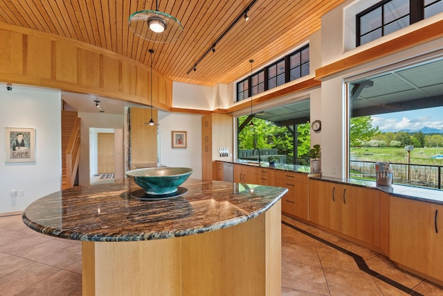 309 Canal St, Bigfork, MT 59911 - kitchen with track lighting, light tile patterned floors, dark stone countertops, a center island, and wooden ceiling