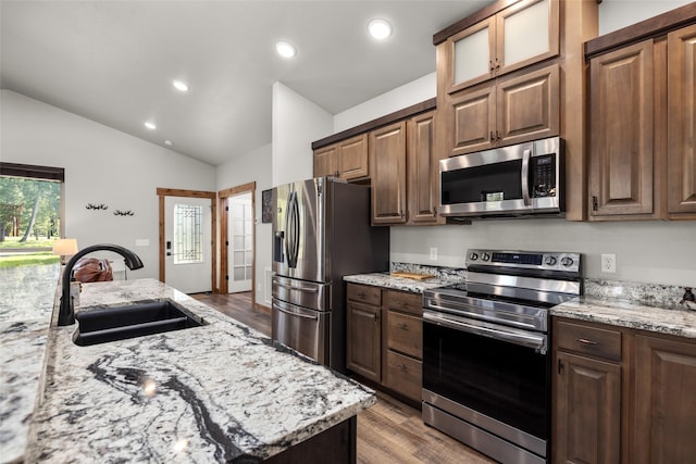 165 Lynx Ct, Seeley Lake, MT 59868 - kitchen featuring appliances with stainless steel finishes, a sink, light wood-style floors, light stone counters, and lofted ceiling