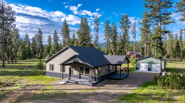165 Lynx Ct, Seeley Lake, MT 59868 - view of front of property featuring an outdoor structure, roof with shingles, a view of trees, a detached garage, and driveway