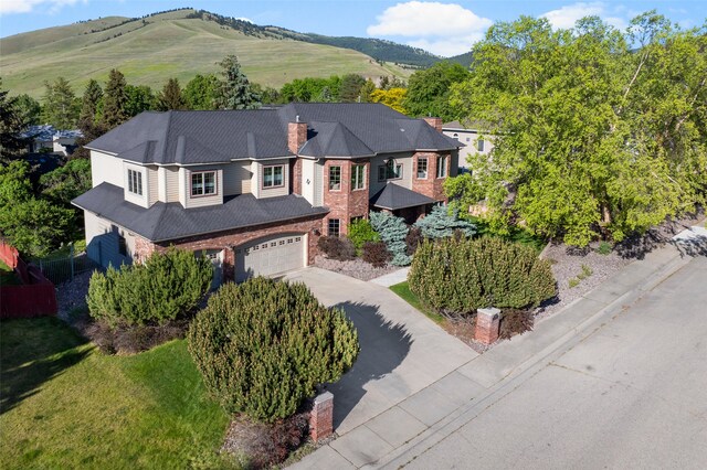 140 Fairway Dr, Missoula, MT 59803 - view of front of house featuring an attached garage, driveway, a chimney, brick siding, and a mountain view