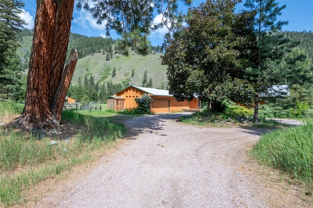 1165 Rock Creek Rd, Clinton, MT 59825 - view of front of house featuring driveway, a forest view, and board and batten siding