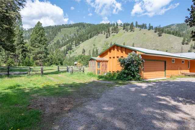 1165 Rock Creek Rd, Clinton, MT 59825 - view of side of home with an attached garage, an outdoor structure, driveway, and a mountain view