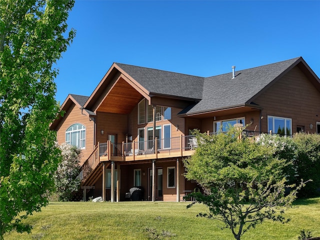 310 Jossie Ln, Kalispell, MT 59901 - back of property featuring a lawn, a deck, a shingled roof, and stairs