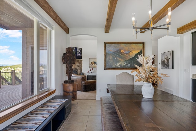 310 Jossie Ln, Kalispell, MT 59901 - tiled dining space featuring beamed ceiling, a fireplace, a chandelier, and arched walkways