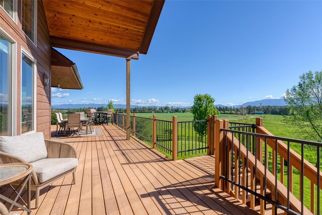 310 Jossie Ln, Kalispell, MT 59901 - deck with outdoor dining area, a rural view, a mountain view, and a lawn
