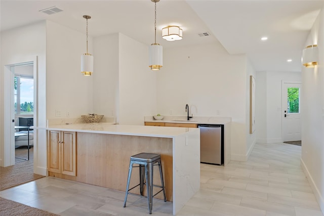 310 Jossie Ln, Kalispell, MT 59901 - kitchen with dishwasher, light brown cabinetry, a sink, a kitchen bar, and light countertops