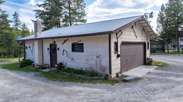 8250 US Highway 2 W, Marion, MT 59925 - view of side of property featuring a chimney, a detached garage, and metal roof
