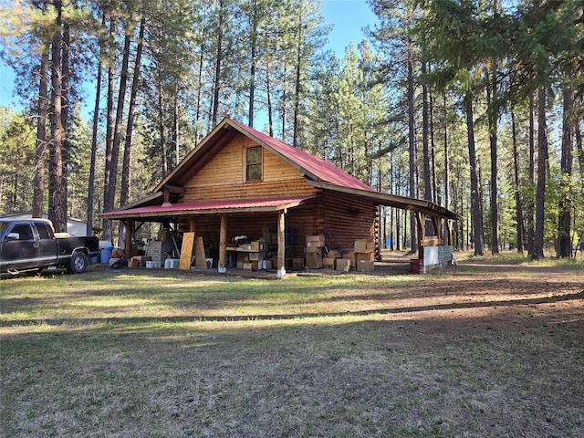 226 Powerline Way, Libby, MT 59923 - view of front of house featuring log exterior, a front lawn, a metal roof, and a forest view
