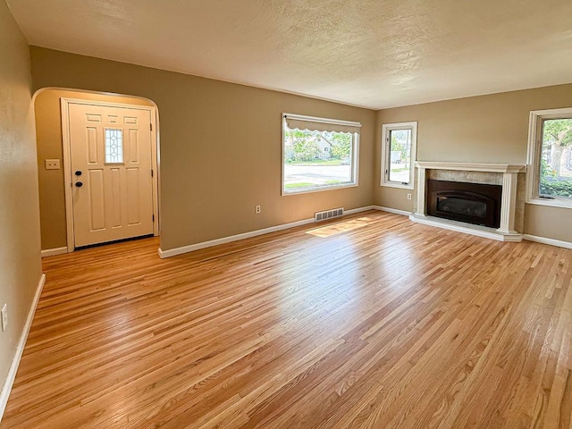2201 6th Ave N, Great Falls, MT 59401 - unfurnished living room with light wood finished floors, plenty of natural light, baseboards, arched walkways, and a textured ceiling