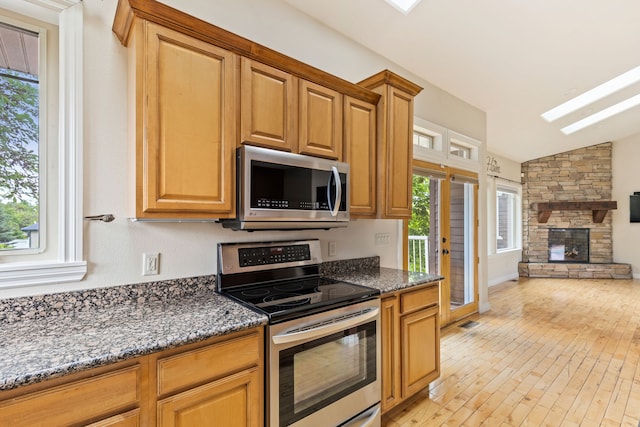 4200 13th Ave S, Great Falls, MT 59405 - kitchen featuring appliances with stainless steel finishes, lofted ceiling, healthy amount of natural light, dark stone countertops, and light wood-style flooring