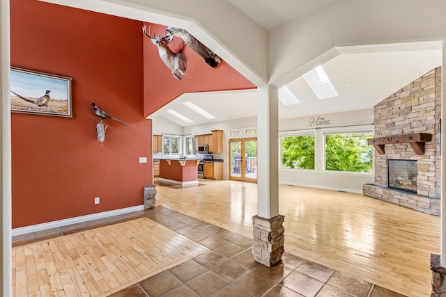 4200 13th Ave S, Great Falls, MT 59405 - unfurnished living room with lofted ceiling, a fireplace, baseboards, a skylight, and healthy amount of natural light