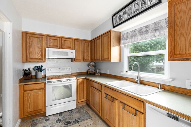 2713 5th Ave S, Great Falls, MT 59405 - kitchen featuring white appliances, a sink, light countertops, light tile patterned floors, and brown cabinetry